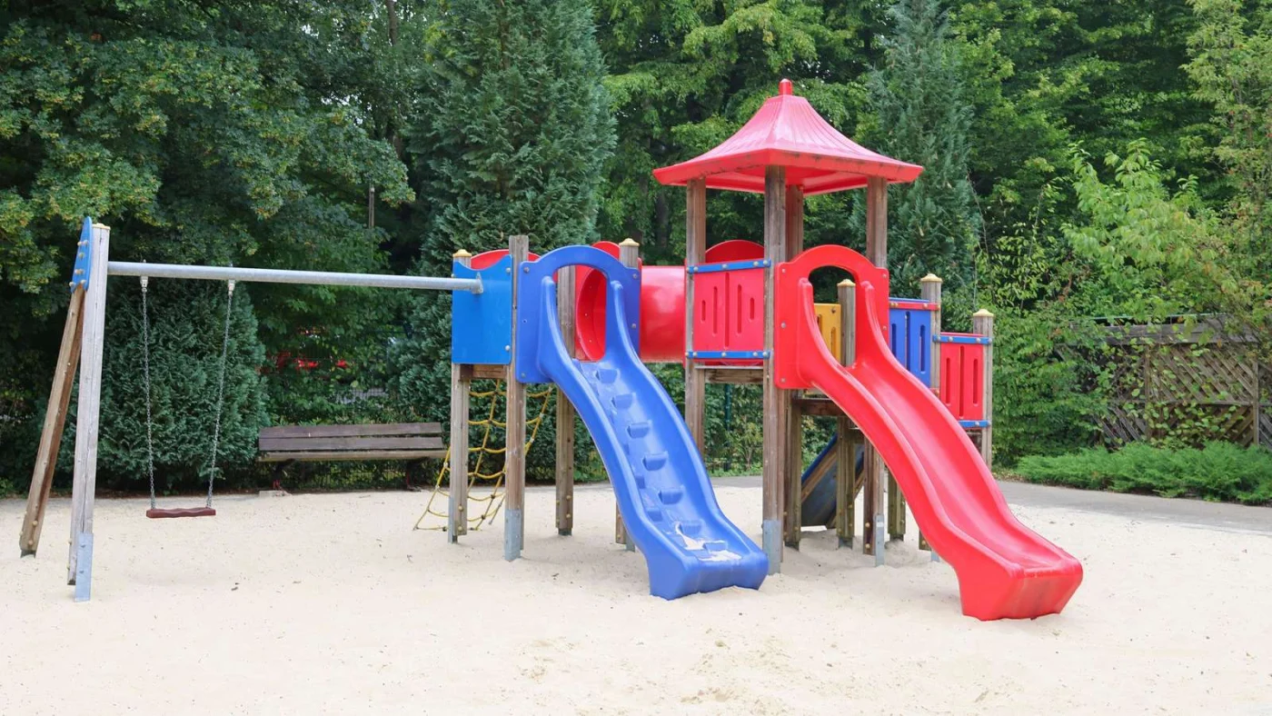 Blick auf den Spielplatz mit Sand und Rutsche.