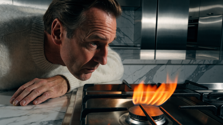 Eine Nahaufnahme eines Gasbrenners, dessen Flamme sich gelb-orange verfärbt.