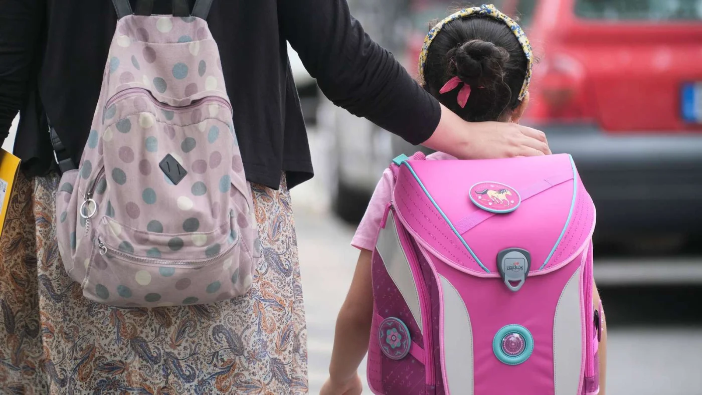Eine Frau legt den Arm um ein Schulkind.