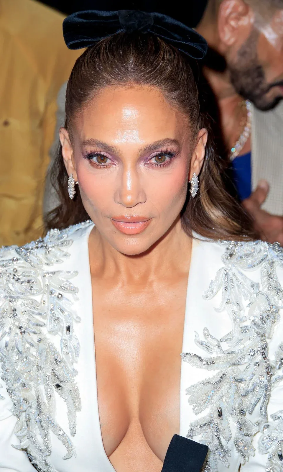 Jennifer Lopez in a white embellished top, with a black bow in her hair.