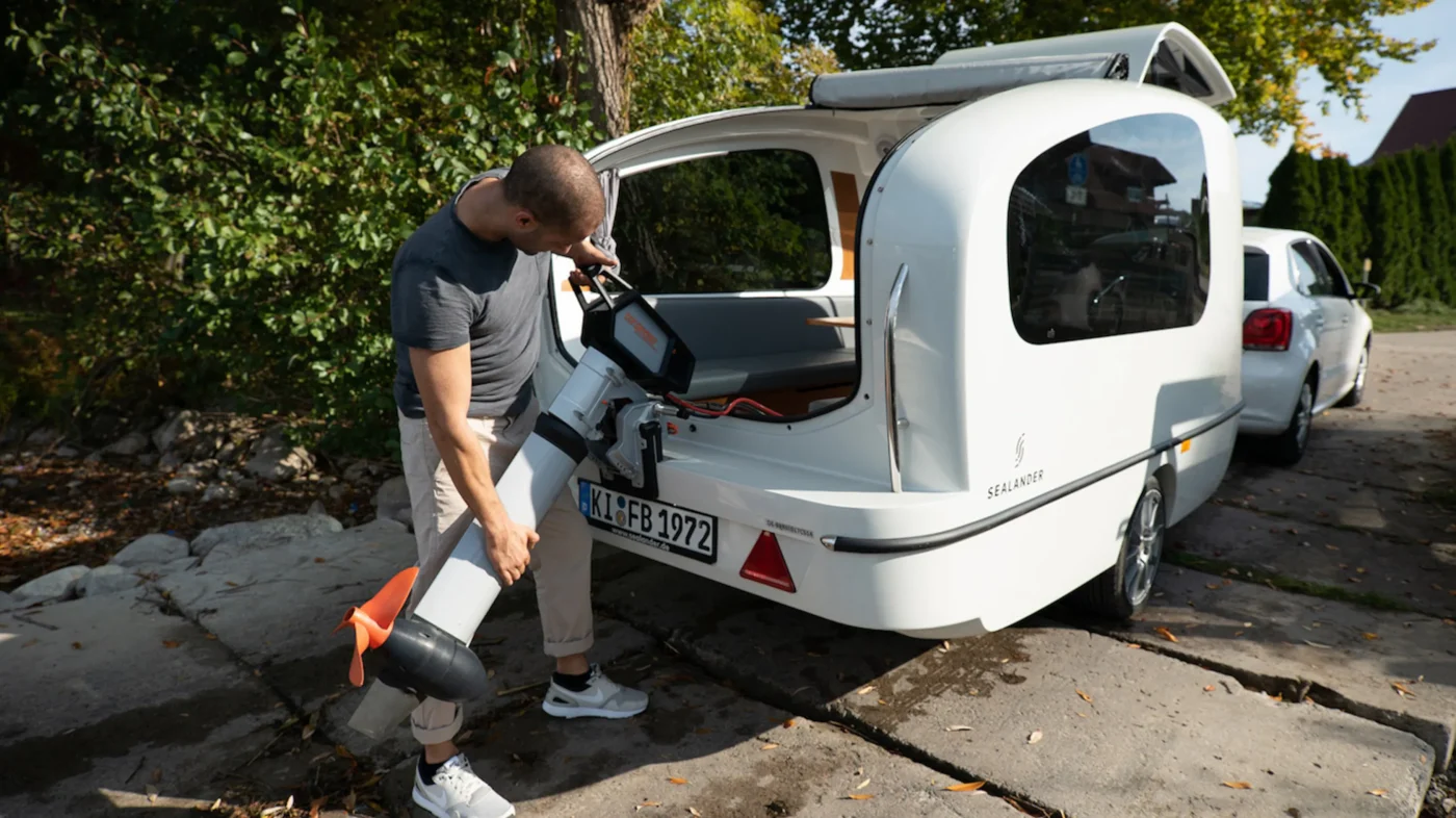 Mann befestigt einen Außenbordmotor am Sealander