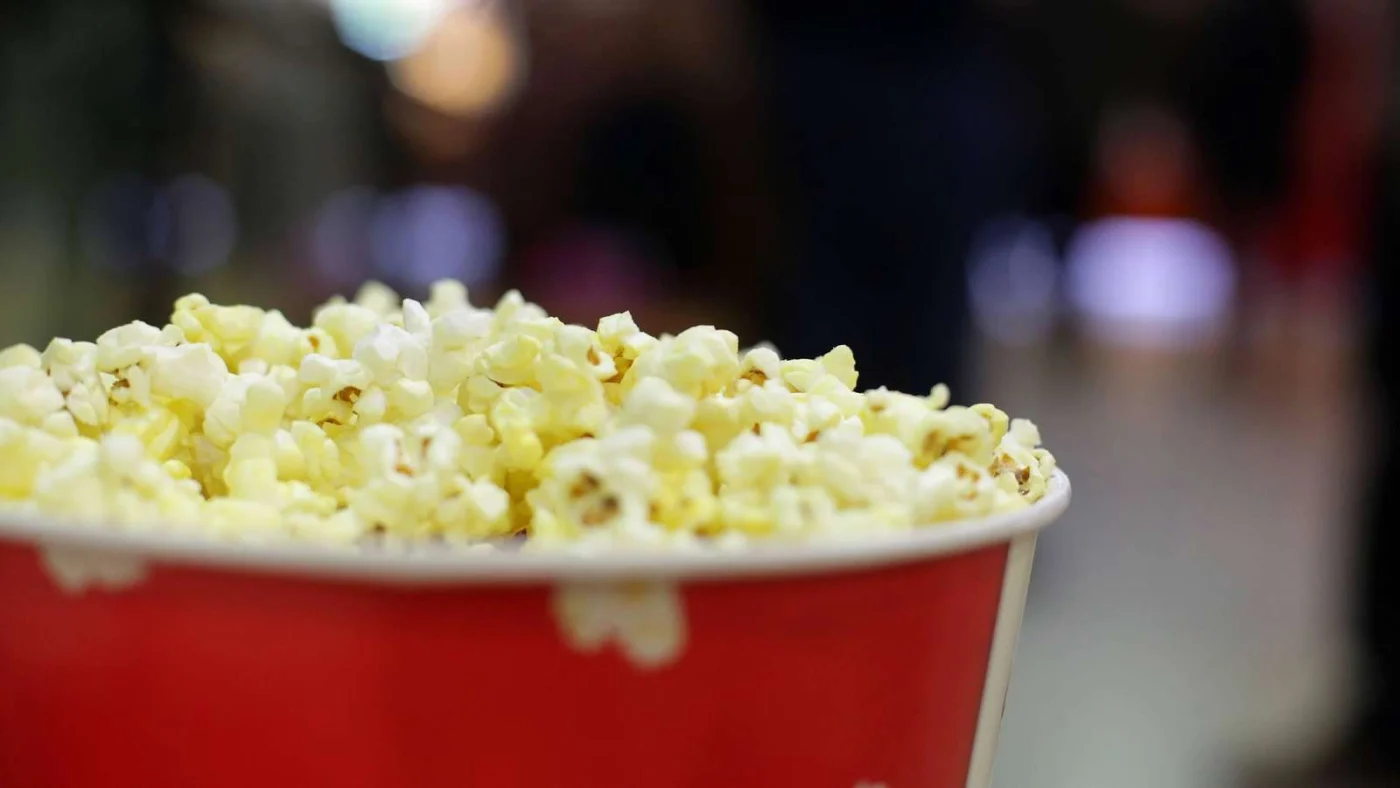 Nahaufnahme eines roten, bis zum Rand gefüllten Popcorneimers im Kino.