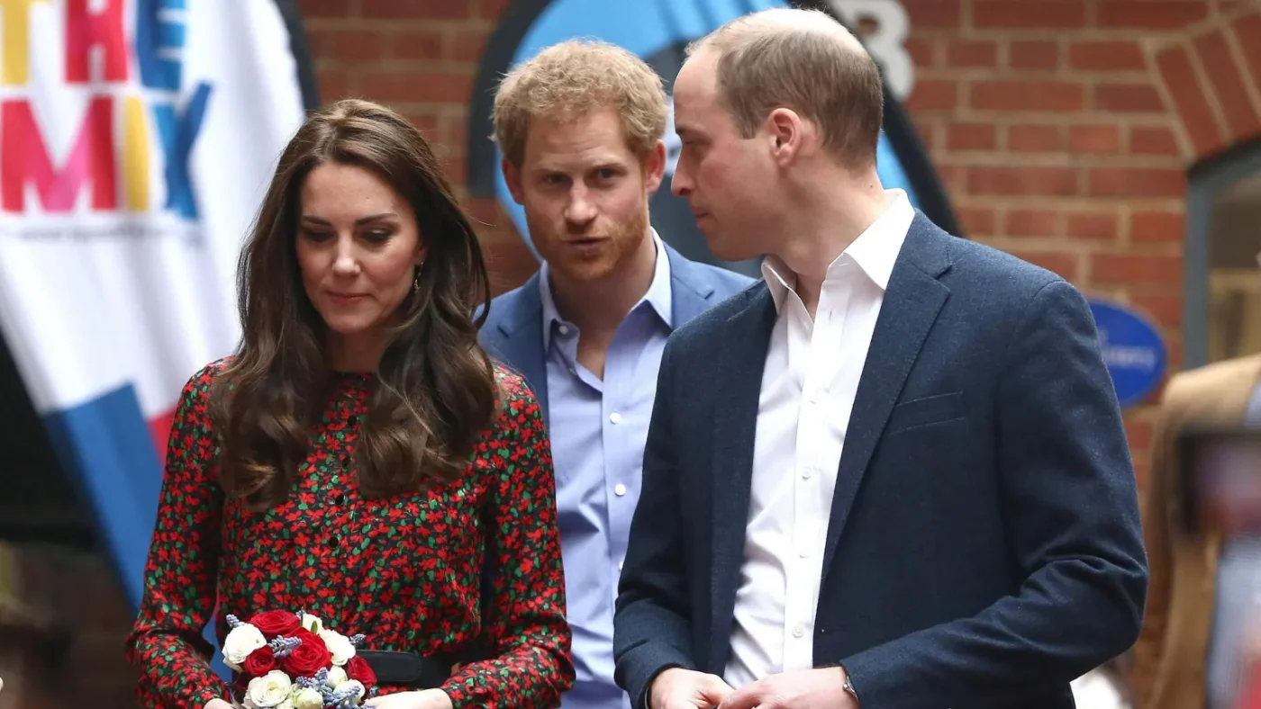 Reuters The Princess of Wales, dressed in a red floral dress, and Prince of Wales, in a blue suit, stand in front of the Duke of Sussex