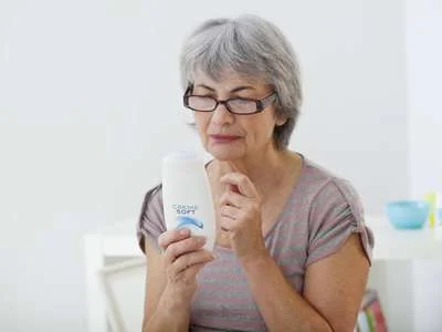 Seniorin liest die Inhalte auf einer Duschgelverpackung.