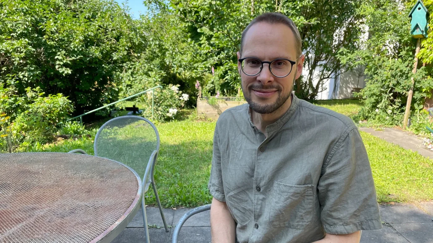 Der Stuttgarter Künstler Daniel Beerstecher sitzt auf einem Stuhl und schaut in die Kamera.