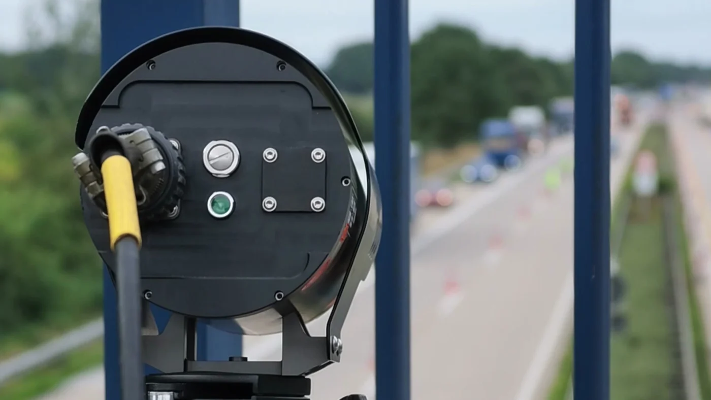 Eine Kamera überwacht von einer Autobahnbrücke aus den Verkehr.