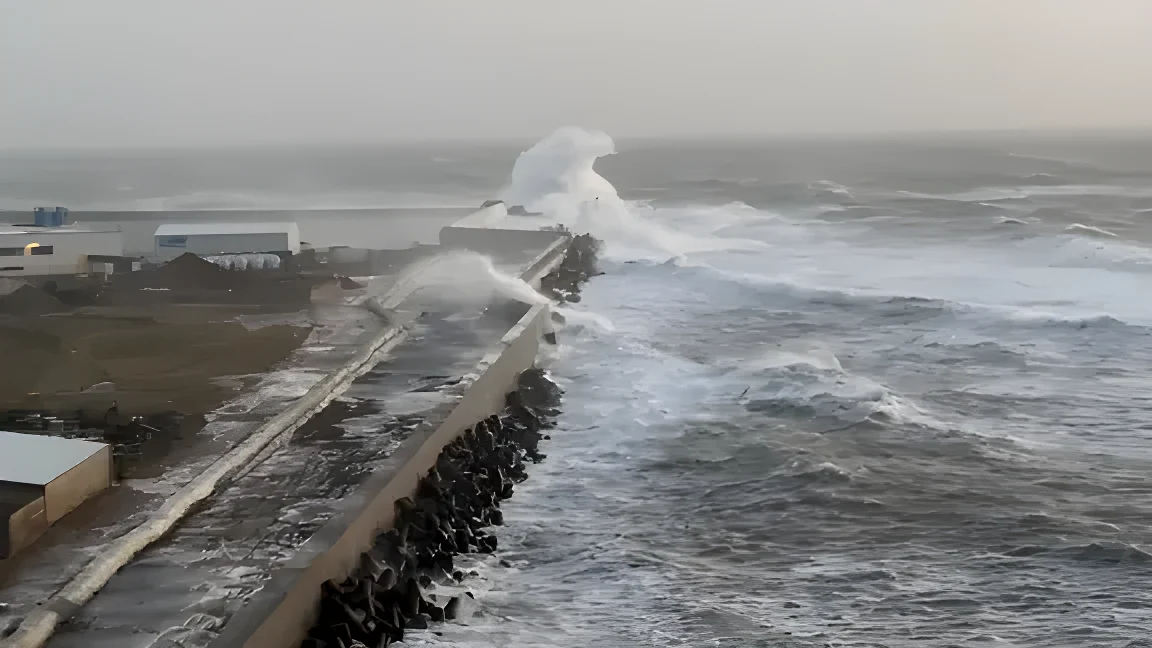 Eine Welle bricht sich an einer Mole