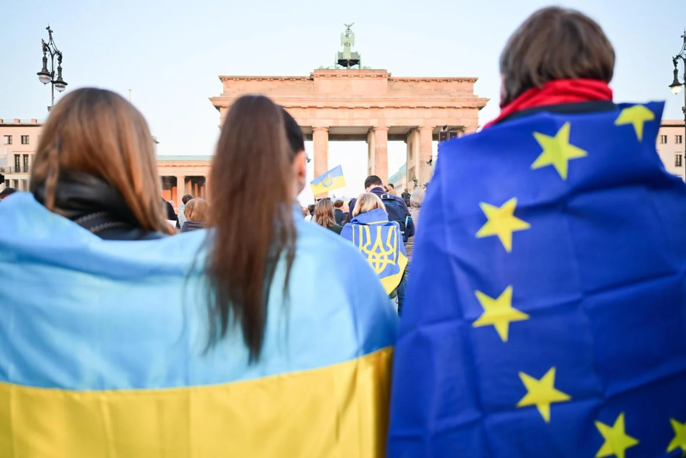 Teilnehmer stehen mit Ukraine- und EU-Fahnen während einer Demonstration für Solidarität mit der Ukraine im März 2025 vor dem Brandenburger Tor.